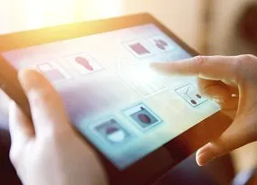 Person steuert die Beleuchtung einer Wohnanlage über ein Tablet. 